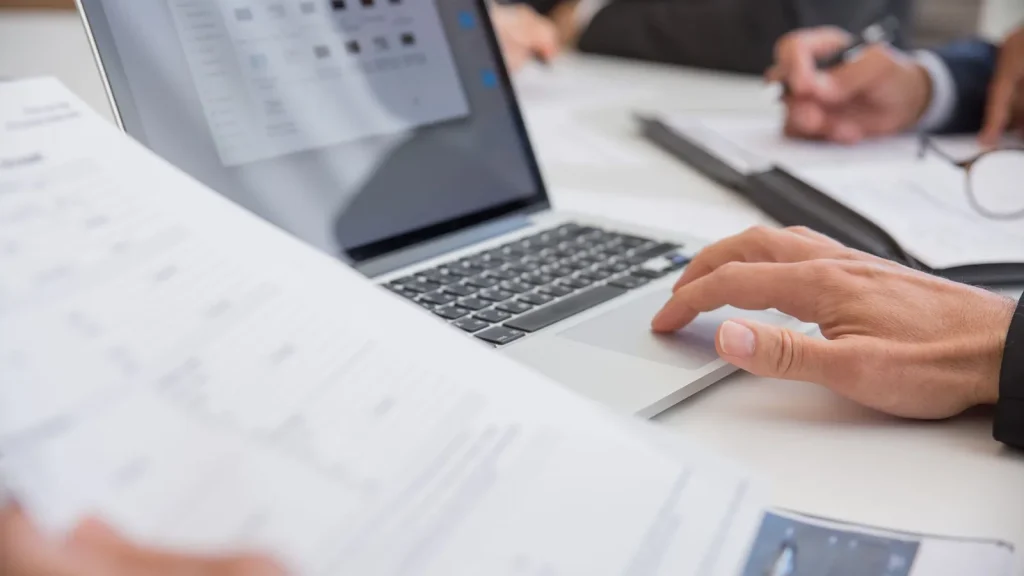 Profesional trabajando con documentos y portátil como alternativa a hojas de cálculo