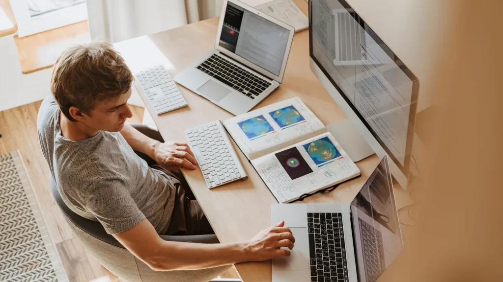 Profesional trabajando con varios equipos informáticos en modalidad de teletrabajo