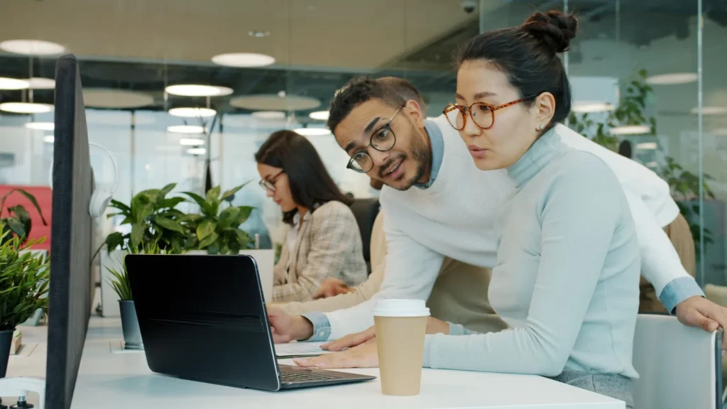Equipo comercial trabajando con clientes y software en una oficina